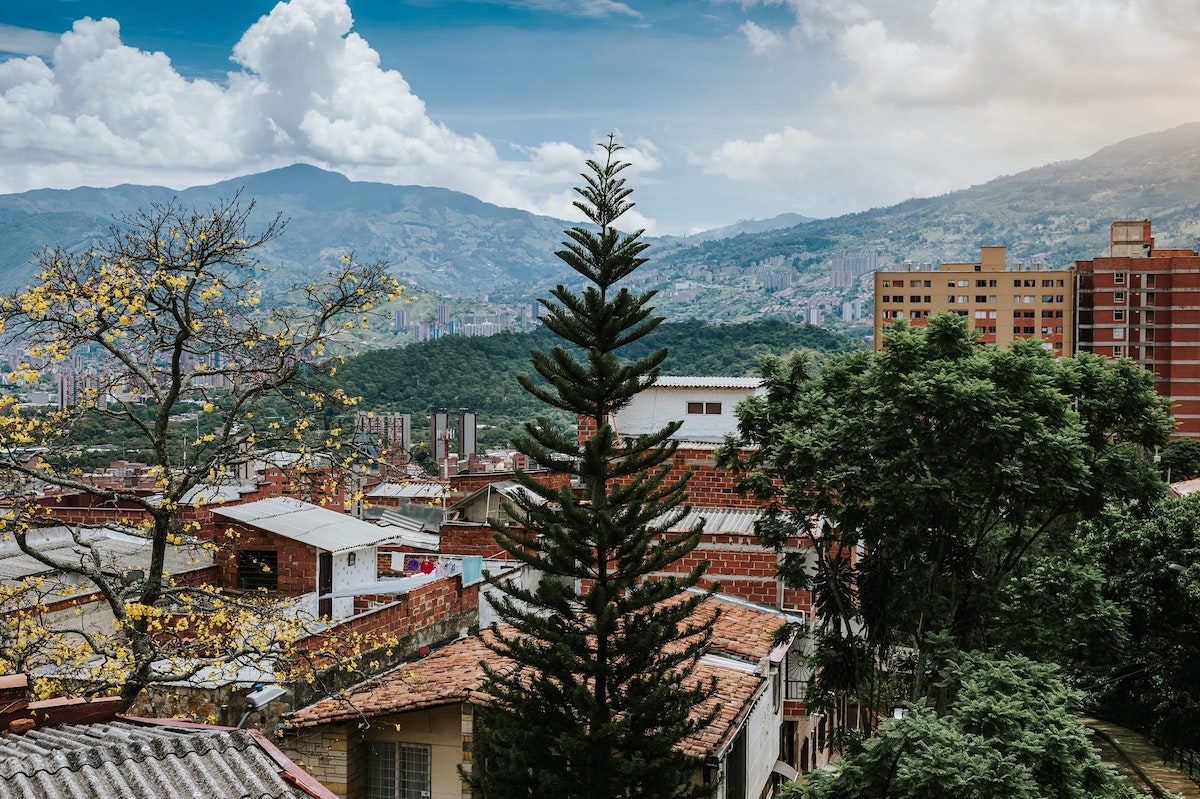 Where To Stay in Medellin: 7 Best Neighbourhoods! | laureles medellin Beautiful landscape of trees and hills overlooking a city.