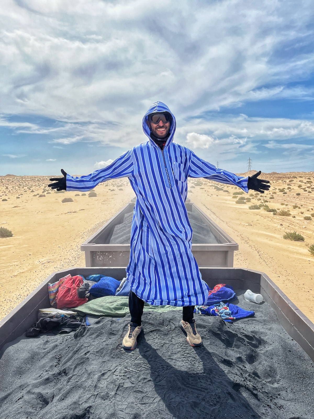 Riding The Iron Ore Train, Mauritania: My Sahara Experience! | local attire iron ore Mauritania A man poses while riding on the iron ore train in Mauritania