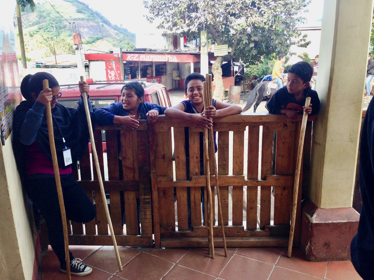 Pacaya Volcano Sunset Hike: An Honest Guide For 2024 | local vendors pacaya volcano Locals talk as they hold wooden walking sticks for tourists for their hike.