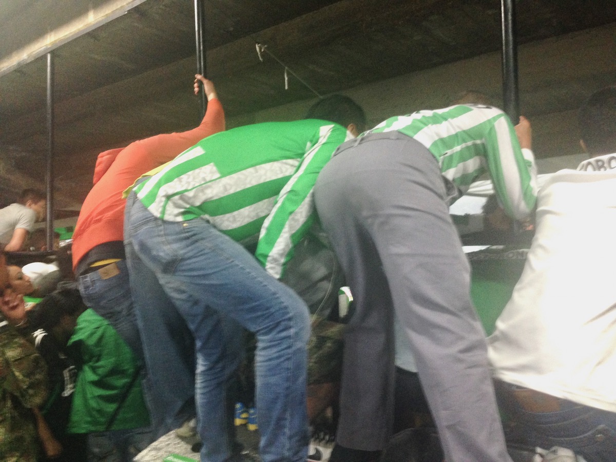 7 Things To Know Before Living in Medellin, Colombia | medellin football fans Football fans in green and white stripes climb over a barricade.