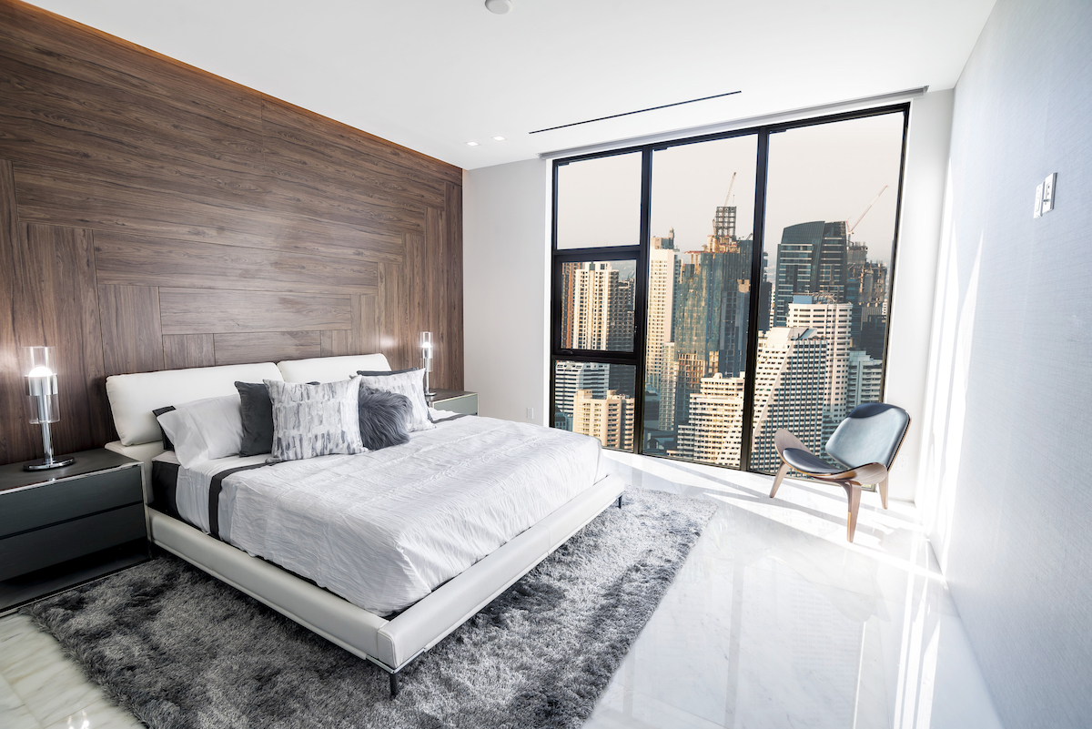 Cost of Living in Bangkok (& The Lies That Bloggers Tell) | modern Bangkok condo with city view Modern and luxurious condo bedroom with white ceiling and wood accents with views of Bangkok skyline