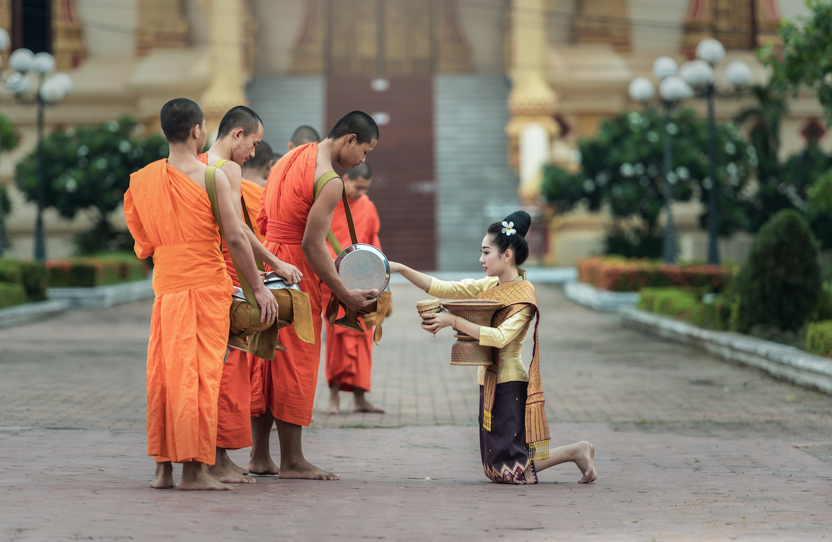 15 Things To Do in Vientiane, Laos (Includes Day Trips) | monks in Vientiane A woman gives food offerings to Buddhist monks in Vientiane, Laos