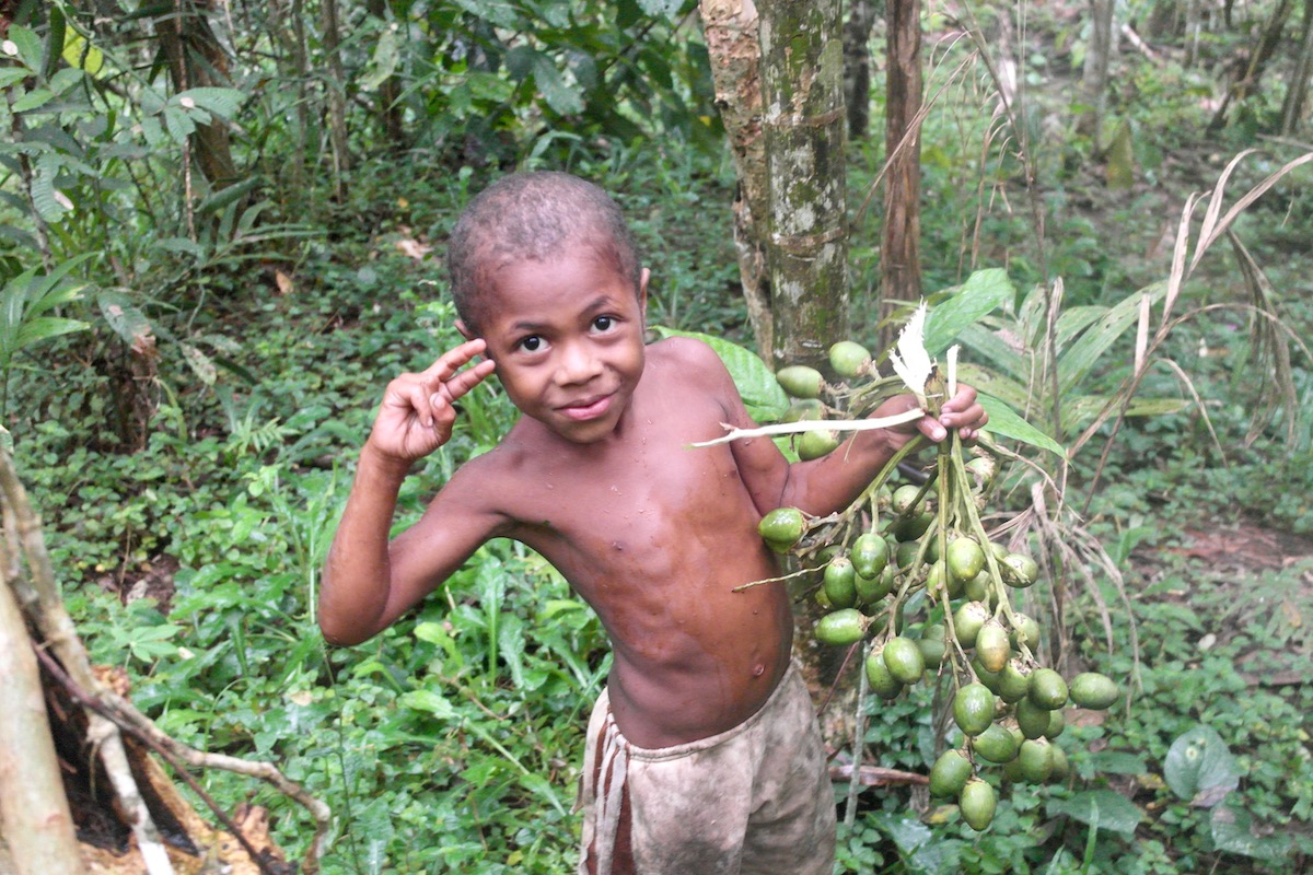 The Tribespeople of Papua New Guinea: A Detailed Guide | papua new guinea child A boy smiles as he collects fruit in the jungles of Papua New Guinea