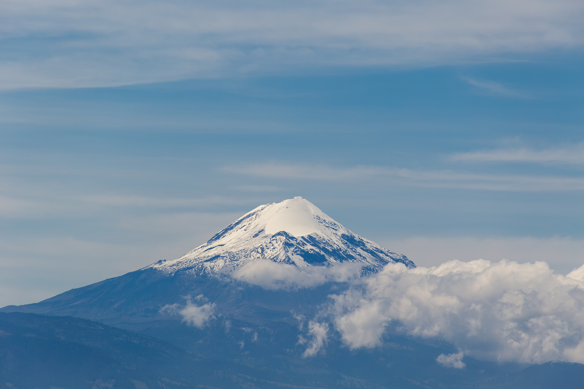 16 Famous Landmarks in Mexico (& How To See Them in 2024!) | pico de orizaba A snow-capped mountain peaks out of the clouds.