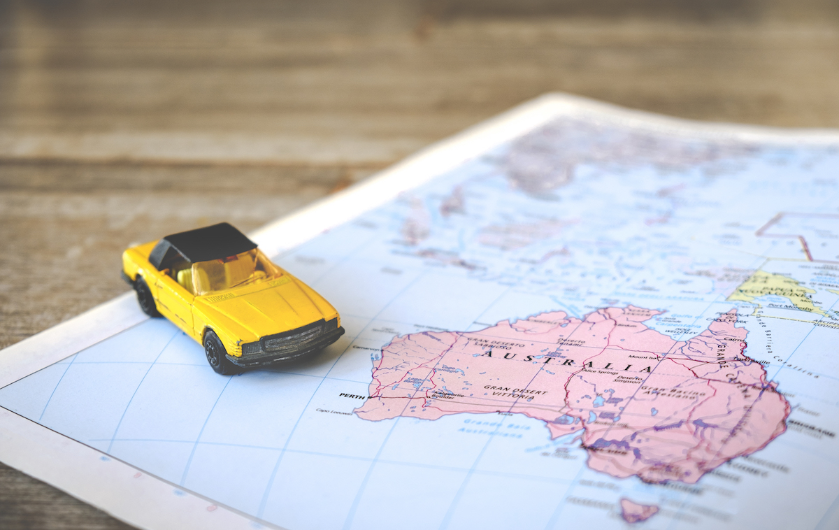How To Plan The Ultimate Australia Road Trip in 2024 | planning australia road trip A toy yellow car on a paper map.