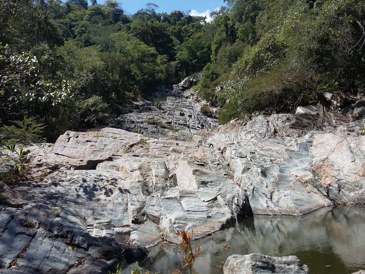 Rocky steep formations surrounded by water and trees.