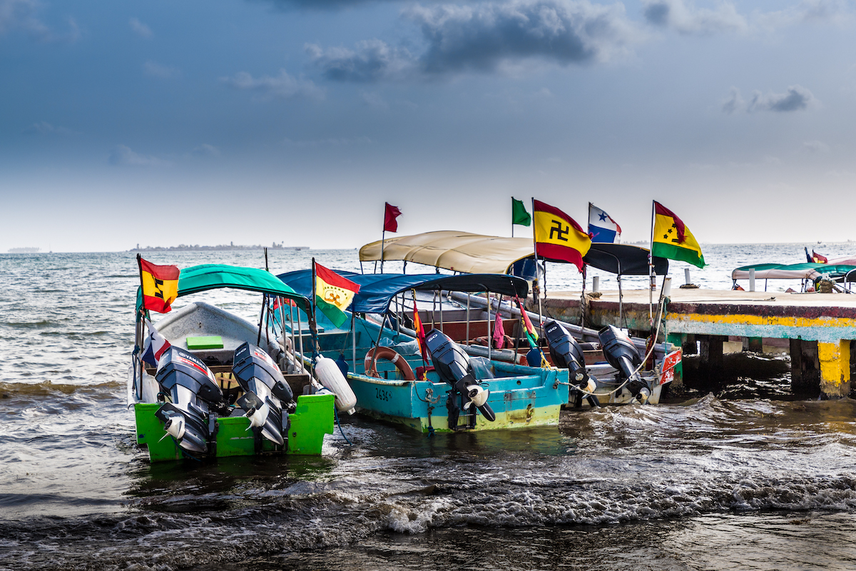 San Blas Islands Travel Guide: Best Things To Do & Logistics | san blas islands travel guide Parked up small boats with colourful flags raised high on each one.