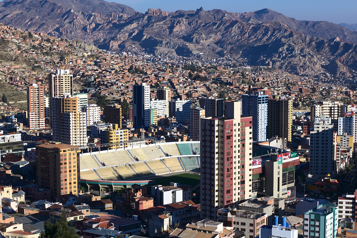 28 Best Things To Do in La Paz, Bolivia & Surrounding Areas | siles stadium la paz A football stadium in a busy city centre with mountains in the background.