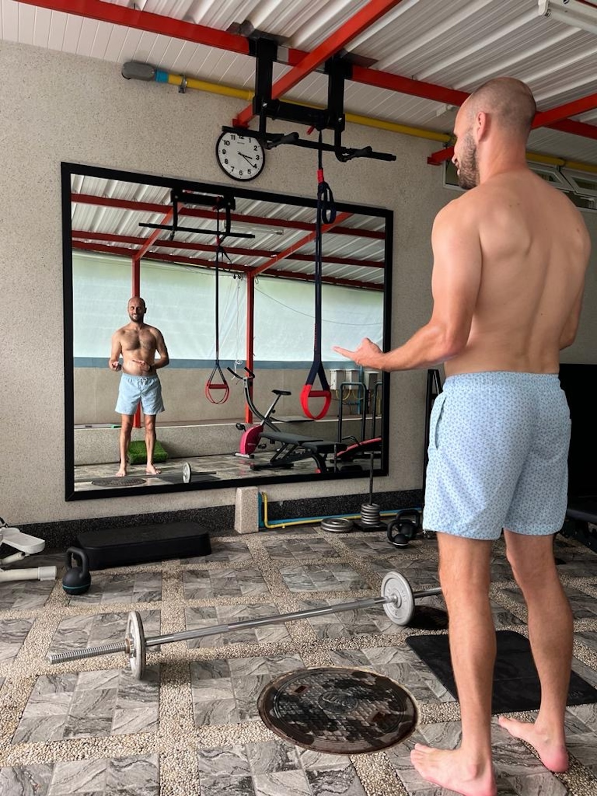 How To Train For High Altitude Hiking: Detailed Guide (From Experience!) | strength training for high altitude 1 Shirtless man stands in front of the mirror in between sets lifting weights